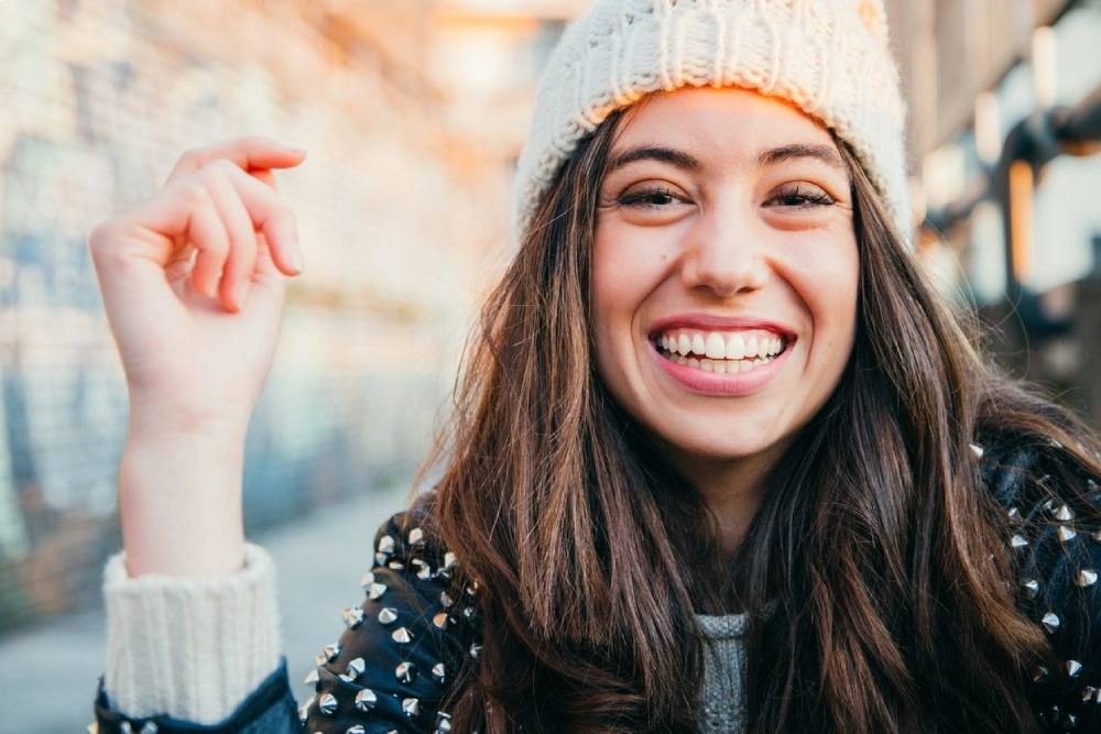 Portrait of a happy and beautiful young woman with woolen cap and leather jacket laughing